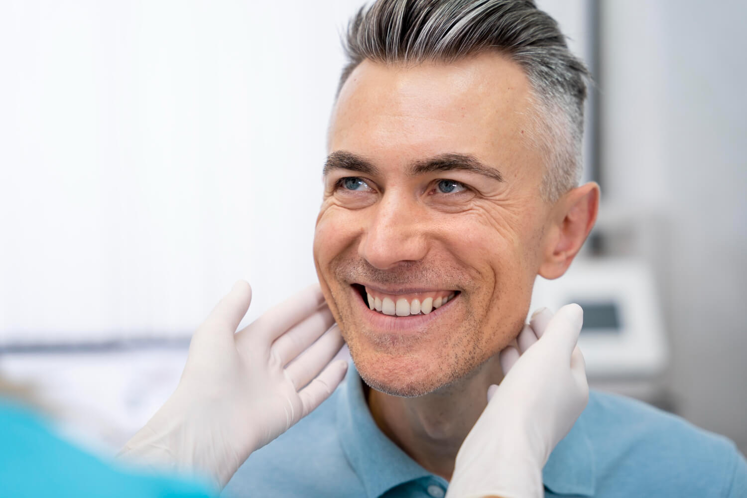 Homem sorridente de cabelos grisalhos recebe avaliação de reabilitação oral na Clínica Cavasi Odontologia em Juiz de Fora.